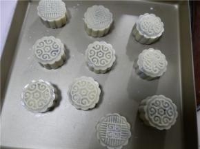在金盘上压出花纹（金盘防粘），月饼表面喷层水防裂。