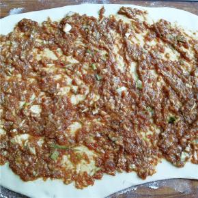 将面团擀成片，将肉馅涂抹于面片上。