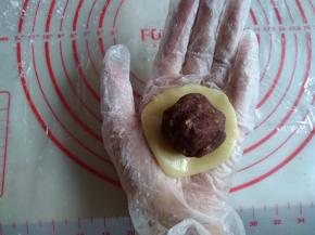 将饼皮在左手手心上压扁，放上馅料