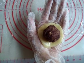 将饼皮在左手手心上压扁，放上馅料