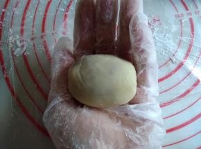 右手按着饼皮慢慢转圈向上推，与馅料紧粘，收口搓圆，再搓成椭圆形，方便入模。表面扑点玉米淀粉或者面粉防粘，拍去多余的粉