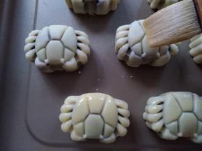 将月饼胚取出，用毛刷沾点蛋黄水，在碗边刮一下再刷在月饼表面，侧面不用刷