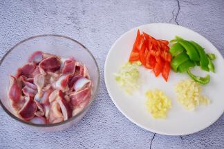 把清洗干净的鸡胗切成薄片，再加入盐、淀粉、食用油抓匀腌制半小时，青红椒去籽切小块，姜蒜葱切末