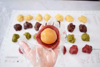 取一份饼皮，放在掌心按压成圆饼形，再放入内馅