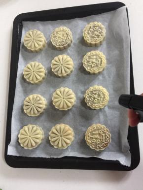 用喷雾瓶从高处薄薄的喷一层水雾在刚刚脱模好的月饼胚上，以免月饼在烤的过程中开裂！

