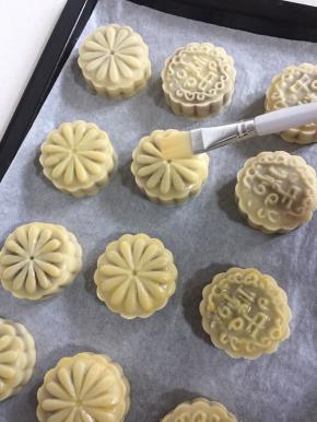 5分钟后出炉，绒毛刷先在碗壁上刮去多余的蛋液，再在月饼表面花纹上薄薄的刷一层蛋液。（鸡蛋加点水搅拌均匀后过筛，再刷蛋液就很均匀了。蛋液不要刷的太多，要不然蛋液多了月饼表面的花纹会模糊。）