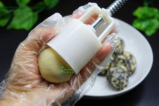 月饼模具均匀撒点糕粉，糕粉就是炒熟的糯米粉，然后放入揉成的月饼小圆，按压出月饼模型出来。