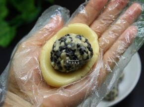 拿一小团月饼皮在手心按压，然后放入柠檬五仁馅馅，包裹起来；