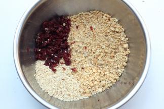 将坚果仁碎粒倒入搅拌盆中，加入熟芝麻和蔓越莓干