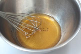 用手抽同方向搅拌两分钟，至糖浆布满细密的气泡，然后将枧水加入搅拌均匀的糖浆中，搅拌均匀