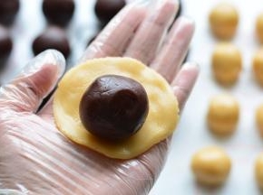 把面团压成圆饼状，中间放上做好的豆沙蛋黄馅，让馅料紧贴着饼皮