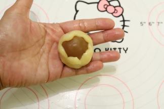 饼皮压成中间稍厚边缘薄的圆片，包住月饼馅，虎口慢慢往上推，收口收紧