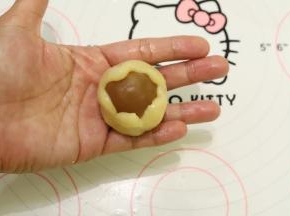 饼皮压成中间稍厚边缘薄的圆片，包住月饼馅，虎口慢慢往上推，收口收紧