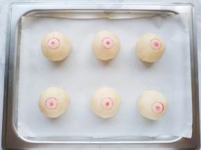 将收口朝下放置，轻轻按压一下，再用瓶盖和筷子蘸取色素给月饼盖上印章。