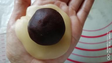 取一面团用手按成圆片，放入馅料。