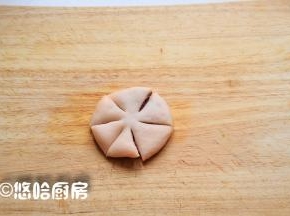 将包好豆沙馅的面团压扁，从外向内切开5个刀口，中间保留一点不要切断。