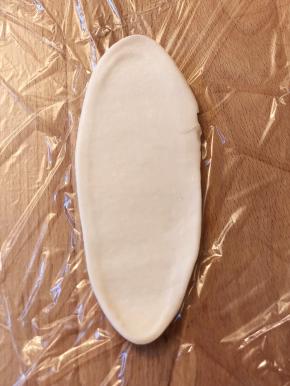 压一下后，从中间位置开始用擀面杖往前推，往后擀，然后从上往下卷起。