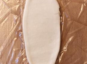 压一下后，从中间位置开始用擀面杖往前推，往后擀，然后从上往下卷起。