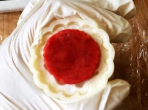 模具撒点粉防粘，把红色放入模具中间，手指粘一点水点一下红色面团，放入绿色面团。压出月饼。