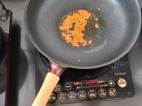 热锅凉油下胡萝卜丁，煸炒片刻。