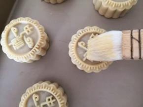 9.	烤箱预热，180度，上下火，中层，先烤5分钟定型，取出刷上全蛋液，要薄薄的一层，这样烤出来的月饼才图案清晰，上色美观，