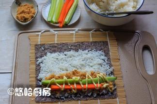 在卷帘上铺一张紫菜，铺上一层米饭，在卷帘的一侧铺一层肉松，放黄瓜条、胡萝卜条，挤上适量的沙拉酱。