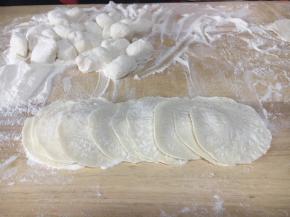 拿出面团再把它们揉匀，取一块小块面团（其它的放回盆里盖盖儿保存），把它用双手搓成长条，再揪成小圆剂子。
把小圆剂子压平，擀成饺子皮，擀饺子要中间厚，周边薄。
