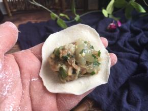 往饺子皮上放适量的饺子馅。