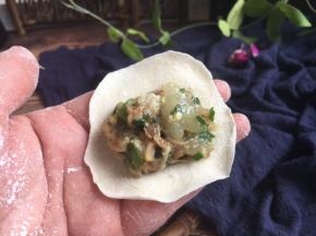 往饺子皮上放适量的饺子馅。