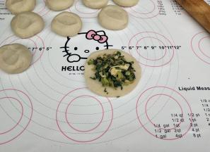 用擀面杖擀成四边薄中间厚的面皮，放上馅料。