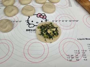 用擀面杖擀成四边薄中间厚的面皮，放上馅料。
