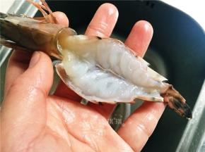 清洗虾。首先剪开虾头部分，剪8分深即可，不要将头剪掉了。接着剪开虾尾，也是8分深不可剪断。再从虾头开口处剪至虾尾开口处。挑出虾线，然后用小刀剖开虾肉如图。清理好的虾放入清水备用。
