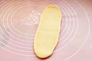 取一块松弛好的面团，用擀面杖擀成长舌状。