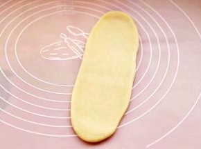 取一块松弛好的面团，用擀面杖擀成长舌状。