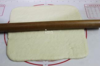 中间发酵好的面团，用擀面杖擀成方形的薄片，大小和烤盘一致。我用烤盘是28*28cm