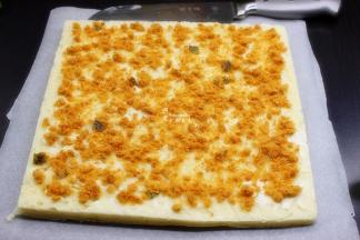 在面包的底面，没有刷蛋液白芝麻的那一面，涂满沙拉酱，并撒上海苔芝麻肉松。