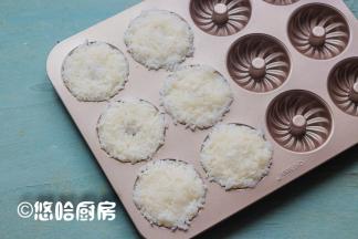 戴一次性手套将米饭放入甜甜圈蛋糕模具中，压紧压实，因为要给小朋友吃，米饭里没有放寿司醋。