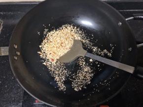 8、接着倒入碎花生翻炒一下。