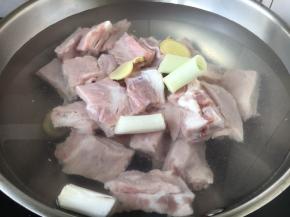 锅里放入小肋排骨，放入凉水，加入姜片和葱段，放入2勺黄酒。