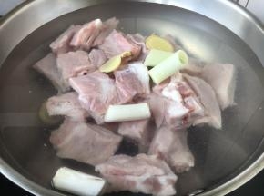 锅里放入小肋排骨，放入凉水，加入姜片和葱段，放入2勺黄酒。
