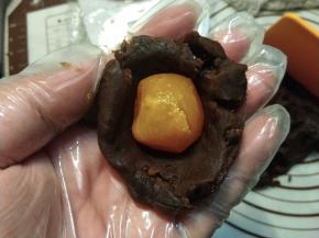 把豆沙馅搓成一个球，压扁，包住蛋黄。
