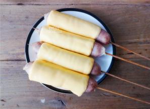 把芝士片去掉外衣，拿起一根香肠放在芝士片上卷起来，包裹着香肠了，依次完成