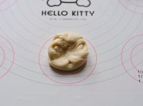 松弛完毕后，取1个酥皮，先在收口处中间按压一下，两边捏起，压扁并擀成

圆形，