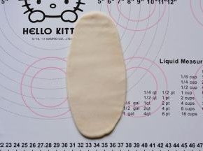 15分钟后进行第一次擀卷：取1个酥皮轻轻压扁，擀成椭圆形薄片