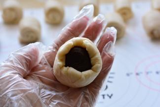 把蛋黄豆沙放在擀成圆形的油皮油酥上，用油皮油酥包住油酥，慢慢用虎口

往上收