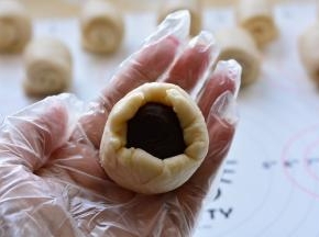 把蛋黄豆沙放在擀成圆形的油皮油酥上，用油皮油酥包住油酥，慢慢用虎口

往上收