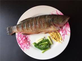 将鱼洗净两面划刀口，不宜割断。生姜切丝，小葱切段。