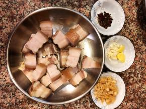 五花肉焯水捞出冲洗干净，入锅加水煲15分钟，捞起切块。锅里的汤汁不要浪费了可以做汤哦。另外准备适量的花椒、八角、姜片、蒜头、半块片糖