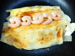 等蛋液微微凝固后，翻转过来刷上蒜蓉辣椒酱摆上虾仁