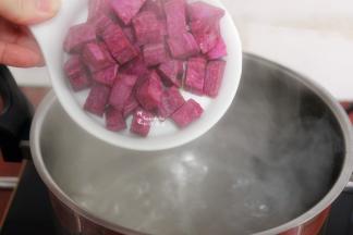 汤锅洗净，倒入4碗食用水，盖上盖子煮沸，把切好的紫薯小方块，倒入锅里。这是4个人的早餐用量，2个紫薯、4包燕麦片，这个配料刚刚好，一家四口一人一碗。